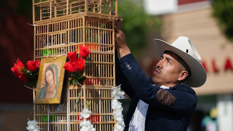 Un vendedor de pájaros prepara una jaula para sus aves antes de la peregrinación anual de...