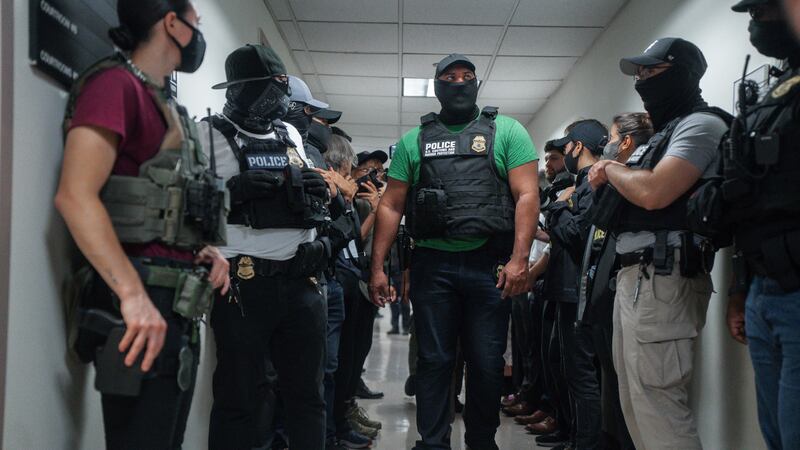FILE - Masked federal agents wait outside an immigration courtroom, July 8, 2025, in New York.