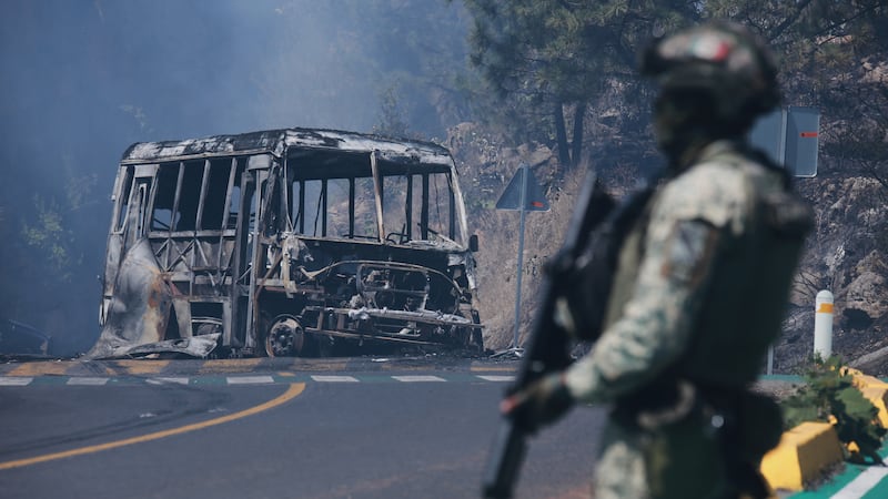 ARCHIVO - Un soldado monta guardia junto a un vehículo calcinado tras ser incendiado en...