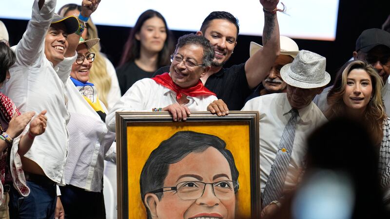 El presidente colombiano Gustavo Petro sujeta un retrato que un partidario le otorgó en un...